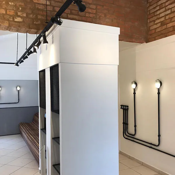 Corredor das salas de atendimento, com tijolo aparente e iluminação em trilho