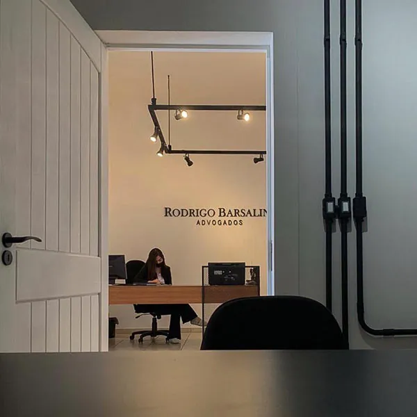 Recepção do escritório vista pela porta, com o nome na parede ao fundo