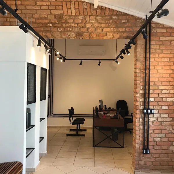 Sala de atendimento com mesa de trabalho e parede de tijolo aparente